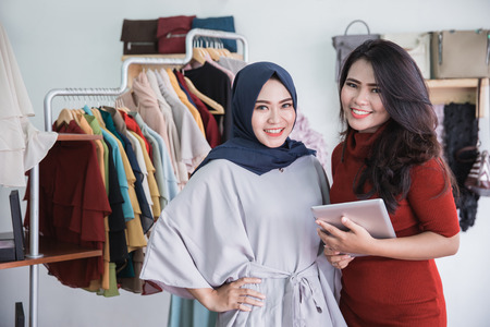portrait of fashion shop owner and her assistant using tablet in fashion storeの写真素材