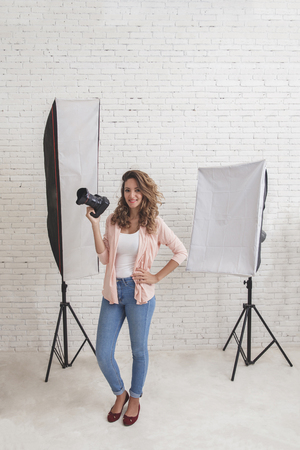 young woman with a camera in the studio with lighting on the bacの写真素材