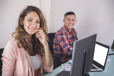 two photographers smiling while editing photos in their computerの写真素材