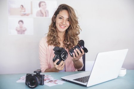 young female photographer attaching the camera lens to camera boの写真素材