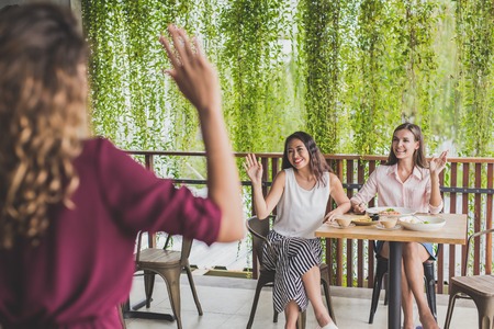 two woman waving hands to their friendsの写真素材