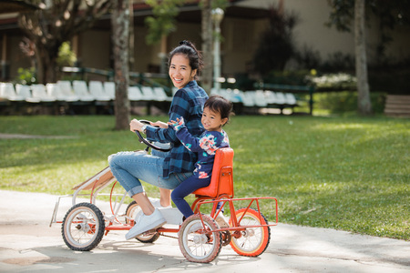mother and daughter riding four wheel bicycleの写真素材