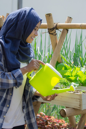 happy muslim woman watering her gardenの写真素材