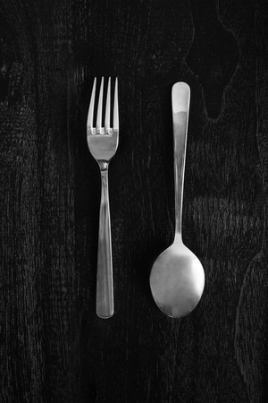 metal fork and spoon on wooden black backgroundの写真素材