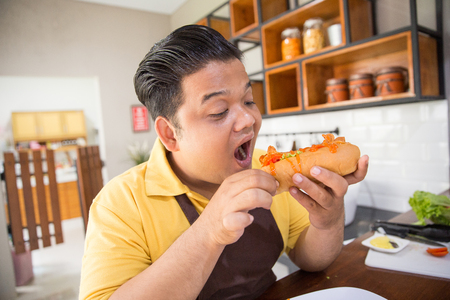 Young fat man eatingの写真素材