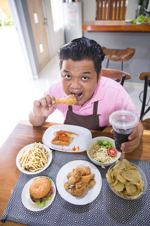 Young fat man eatingの写真素材