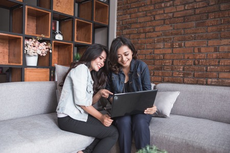Two female friends activity using laptopの写真素材