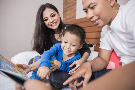 boy reading bed time story with parentの写真素材