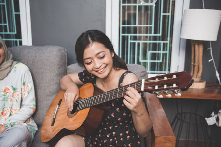 portrait of young asian woman playing guitar with friendsの写真素材