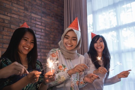 Happy group of friends lighting sparklers and enjoying the moment together. celebration and new year partyの写真素材