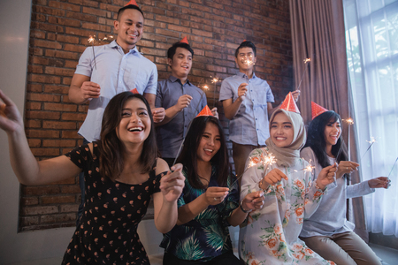 Happy group of friends lighting sparklers and enjoying the moment together. celebration and new year partyの写真素材