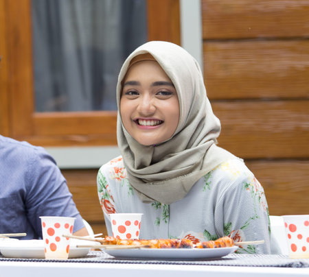 portrait of muslim woman smiling to camera while eating lunch