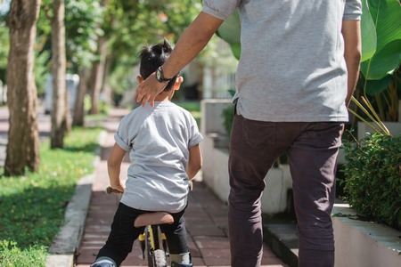 kids ride bicycle push by his fatherの写真素材