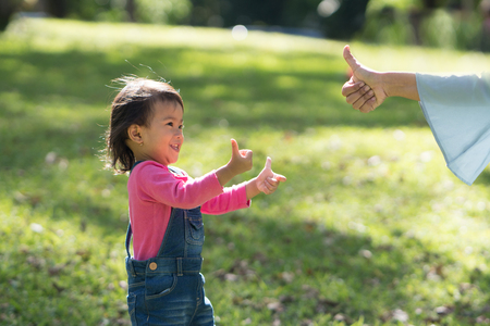 mother showing thumb to her daughterの写真素材
