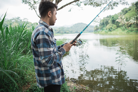 man on the riverbank fishing fishの写真素材