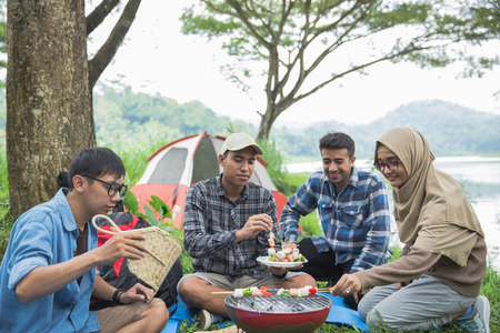 Friends making a barbecue together outdoorsの写真素材