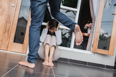 couple fight and abuse concept. domestic violence. woman sitting in fear kicked by his manの写真素材
