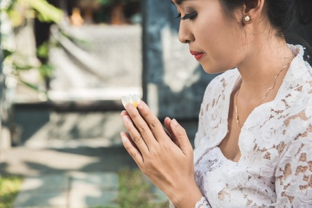 balinese woman praying at temple on small shrines in housesの写真素材