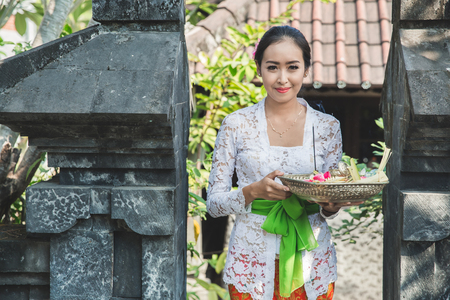 balinese woman wearing traditional clothes bringing canang sariの写真素材