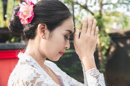 balinese woman praying at temple on small shrines in housesの写真素材