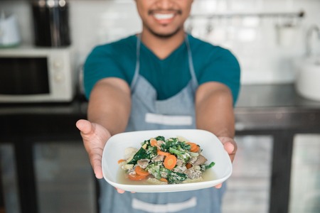 man with apron carrying foodの写真素材
