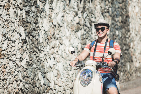 young backpacker riding motorbike during vacation on sunny day