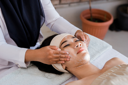 Young woman enjoying massage with mask creamの写真素材