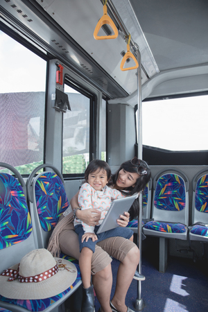 woman is holding her daughter in her lap and showing tablet on tの写真素材