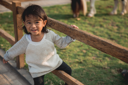 Little girl climbs wood fenceの写真素材