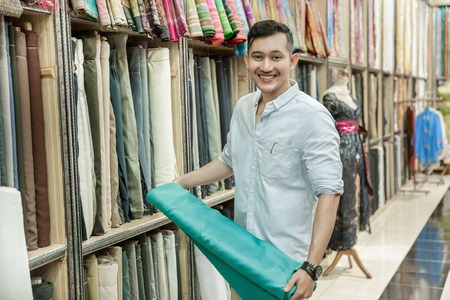 young man choosing material for clothesの写真素材