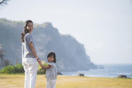 woman and his daughter walking around park looking back at camerの写真素材