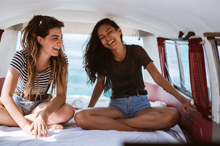 happy young women sitting inside of retro vanの写真素材