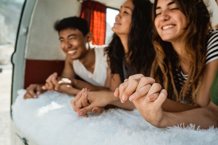 happy young people holding hands inside a car in beachの写真素材