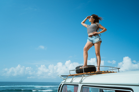 Beautiful woman enjoy road trip nature standing on the roofの写真素材