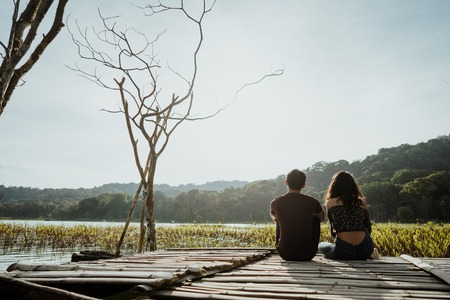 couple sitting on a floating wooden board on a lakeの写真素材
