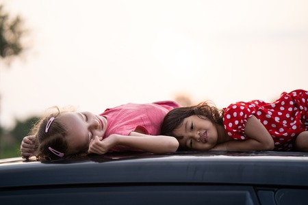 kid laying on top of the car during the vacationの写真素材