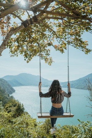 woman portrait enjoying nature from a hill top sitting on a swinの写真素材