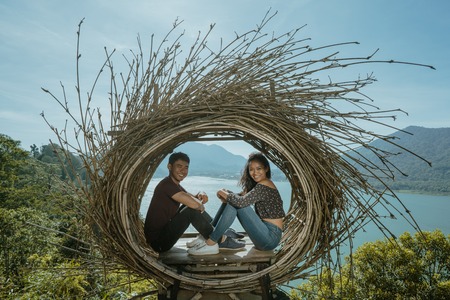 asian couple sitting on their nest on top of the hillの写真素材