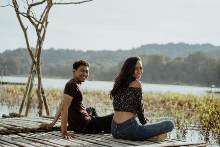 couple sitting on a floating wooden board on a lakeの写真素材