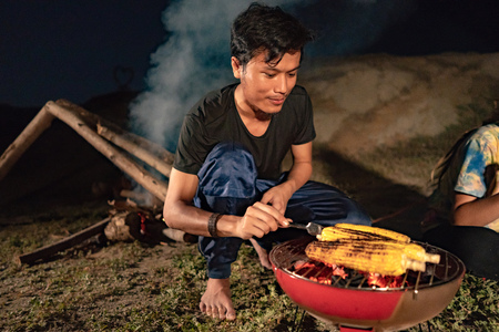 A group of friends having fun camping, eat roasted cornの写真素材