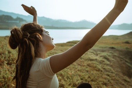 Portrait of woman with raised hands on beautiful sunriseの写真素材