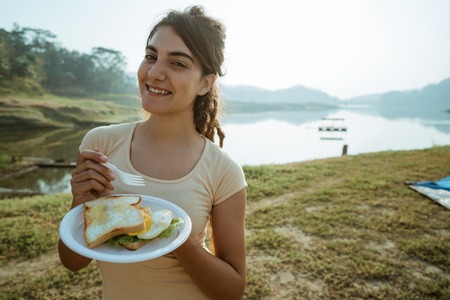 A woman enjoy happy breakfast in side lakeの写真素材
