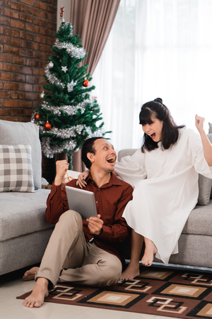 excited couple raise their arm when using tabletの写真素材