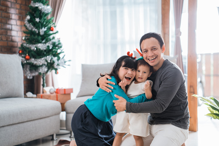 portrait of father, mother and little daughter hugging each otherの写真素材