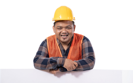portrait of happy handyman with helmet and uniform leaning on white boardの写真素材