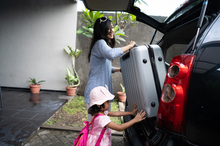 mother put suitcase in the car trunkの写真素材