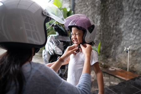 mother help her child to put on a helmetの写真素材