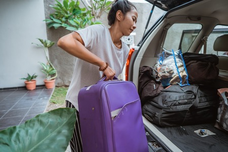 portrait of young asian woman lifting a suitcase when go travelの写真素材