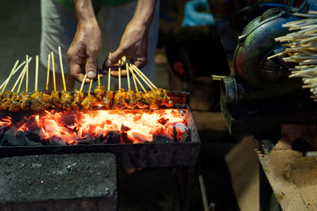 portrait of a cook hands grill a sate on the folding grill shelf