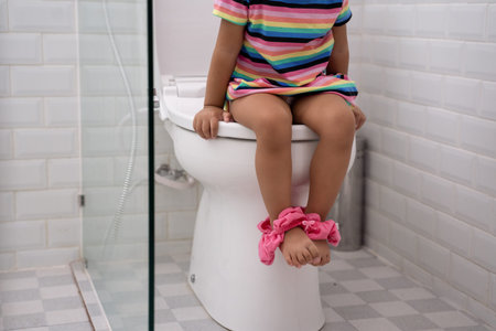 toddlers feed while sitting on toilet with pants down